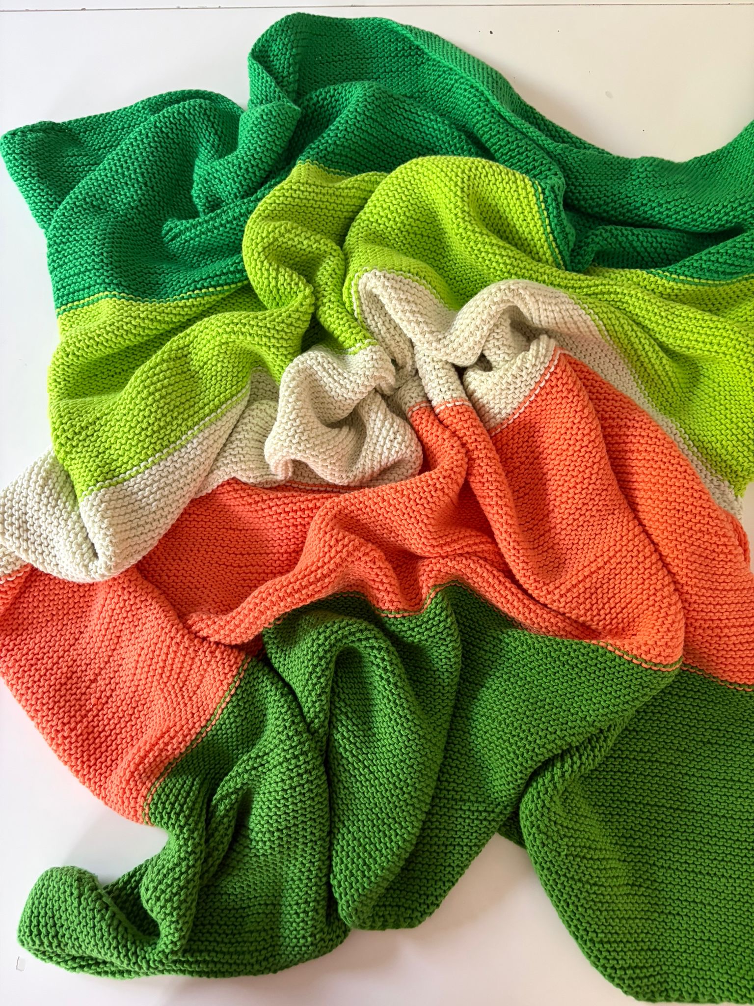 Macaron Blanket loosely gathered on a white surface, showing the full drape and stripe sequence