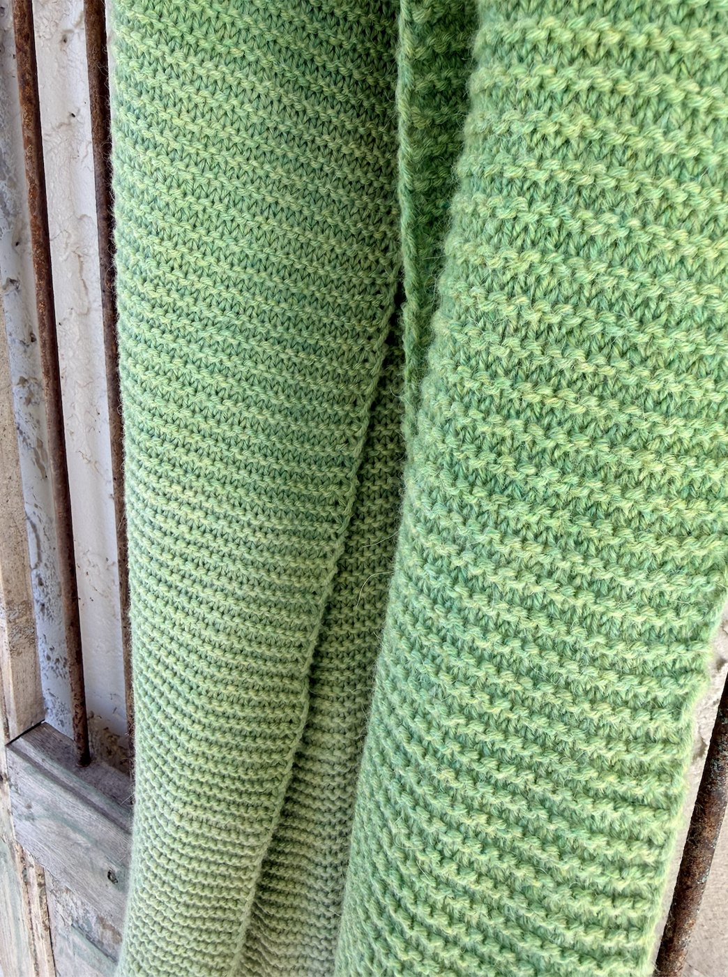 Close-up of the garter-stitch gradient hanging against weathered wood