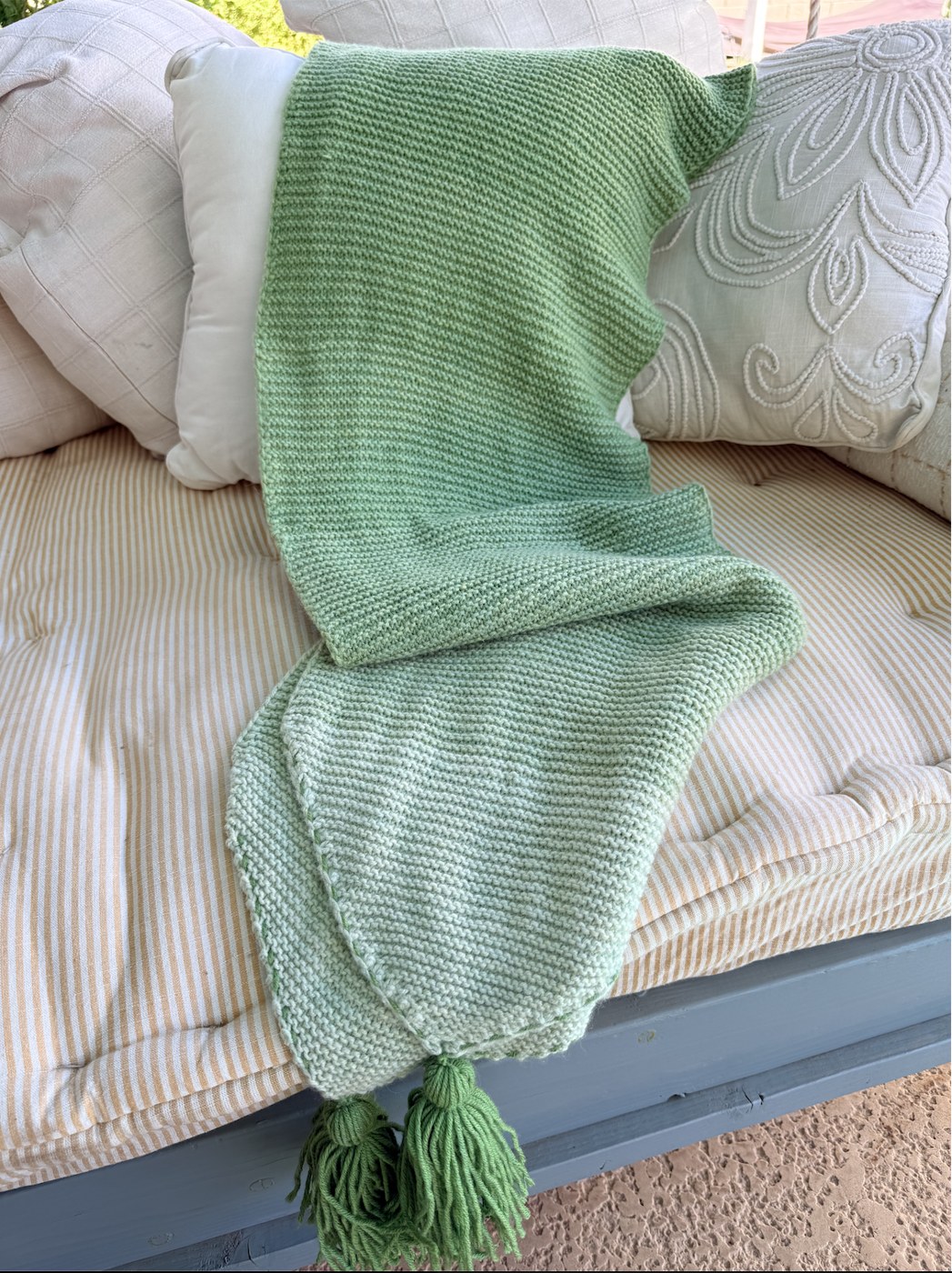 Shades of Nine wrap laid along a cushioned bench with tassels